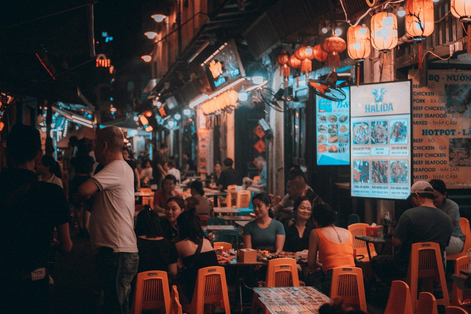 Diners eating at small street-food tables in Hanoi at night