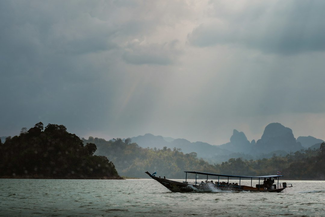 Longtail boat crossing the limestone landscape of Khao Sok Lake, Thailand