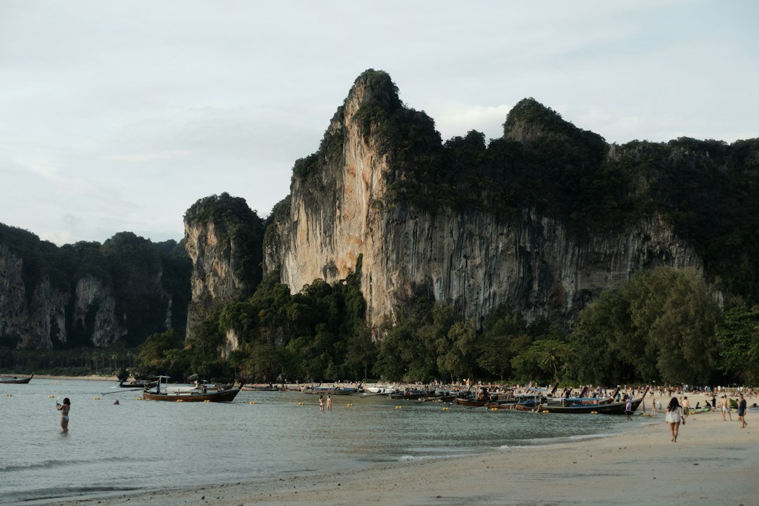 Longtail boats beside limestone cliffs on a Thailand beach