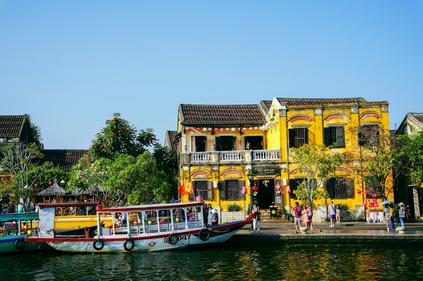 Boats and yellow historic buildings on the Hoi An riverfront